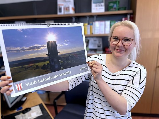Stadtmitarbeiterin Michelle Enge mit dem neuen Jahreskalender 2023, der ab sofort in den B&uuml;rgerb&uuml;ros erh&auml;ltlich ist.  (Foto: Ren&eacute; Wei&szlig;bach)
