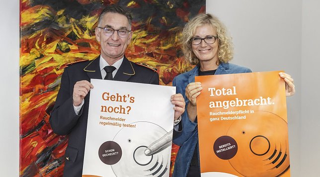 Bild: Hartmut Ziebs, Pr&auml;sident des Deutschen Feuerwehrverbandes (DFV), und Claudia Groetschel, Sprecherin der Initiative Rauchmelder retten Leben stellten gemeinsam die Plakate zum Rauchmeldertag 2017 vor.