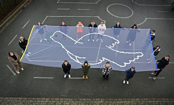 Die Klassensprecher der Regelschule sowie Schulsozialarbeiterin Anna Laura Schneegans (obere Reihe, Erste von rechts) und Werkenlehrer Jens Arand (obere Reihe, Zweiter von rechts) pr&auml;sentieren das Friedensbanner.  (Foto: Regelschule Breitenworbis)